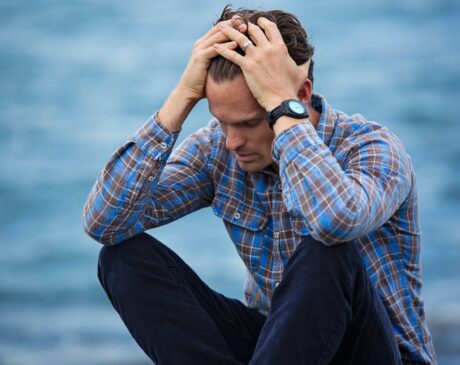 man in blue and brown plaid dress shirt touching his hair